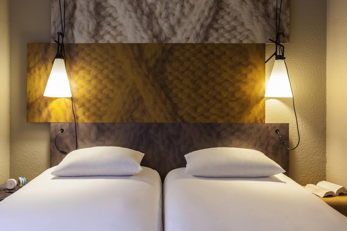 A hotel room with two beds, a marble headboard, and pendant lights.