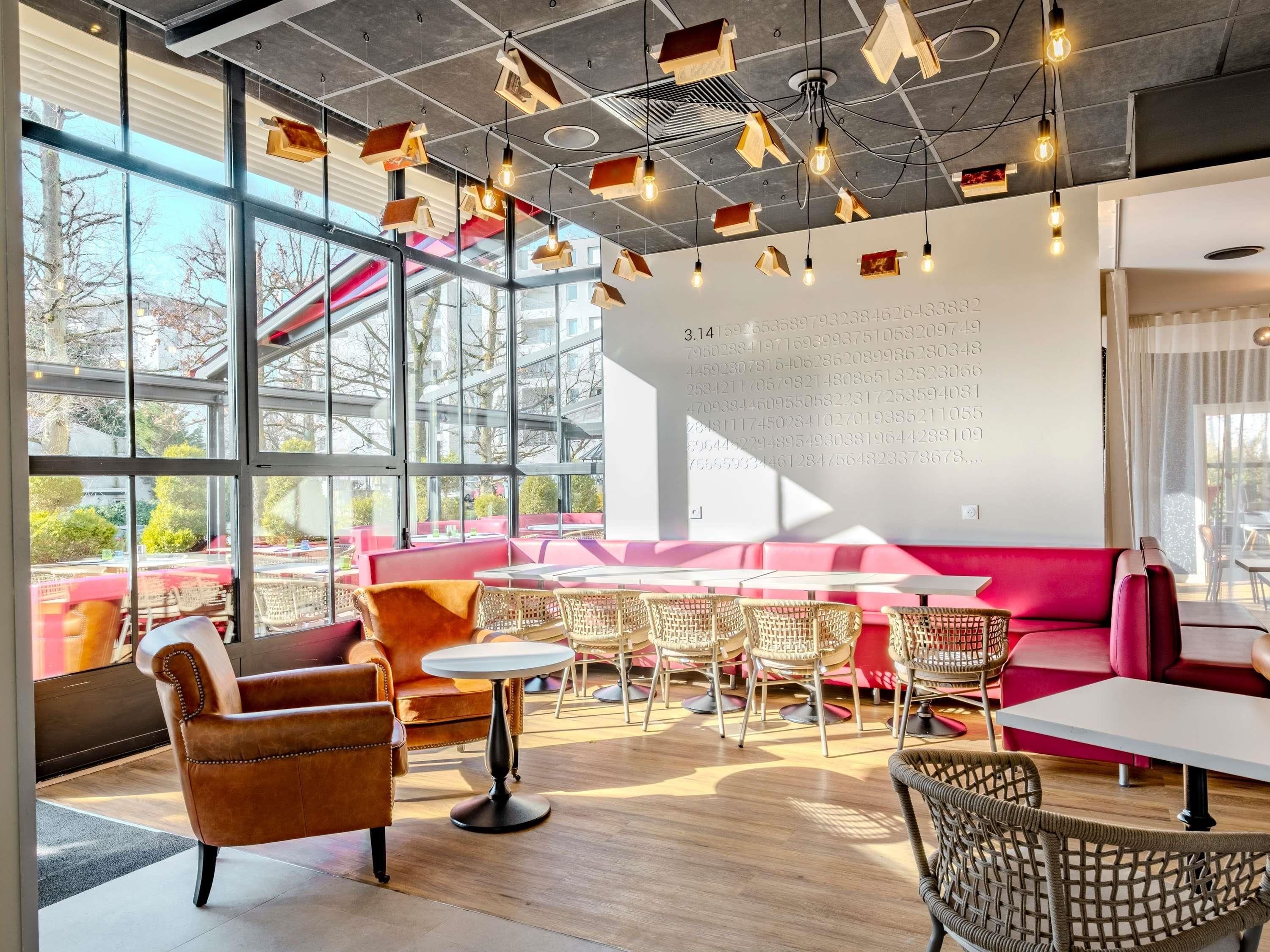 Een modern interieur met grote ramen, een zithoek met een rode bank en een wand met cijfers.