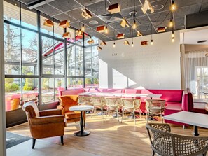 Un intérieur moderne avec de grandes fenêtres, un coin salon doté d’un canapé rouge et un mur orné de chiffres.