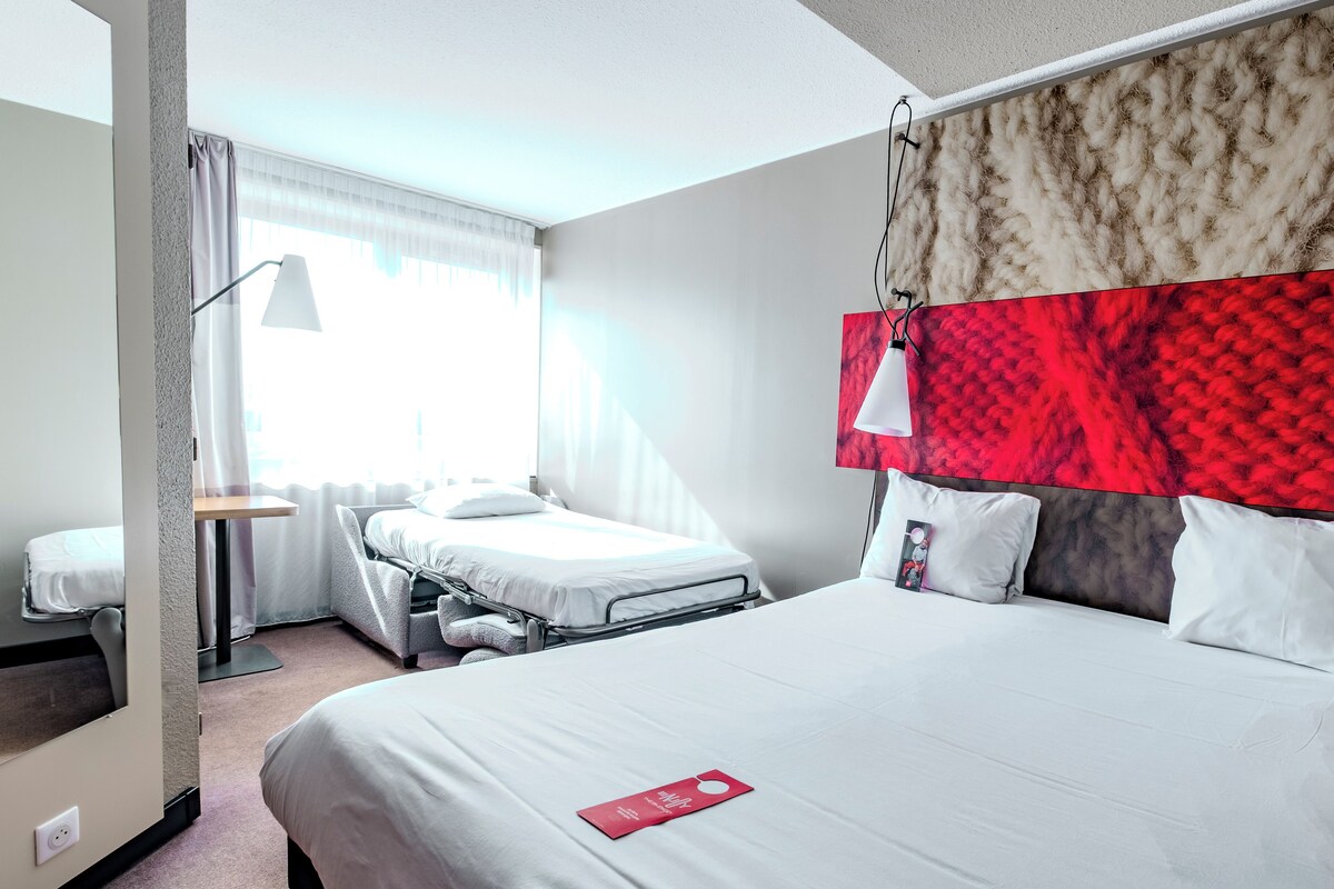 Una habitación de hotel con una cama grande, un escritorio, una silla y una ventana con cortinas.