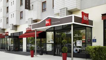 Un hotel con fachada moderna, entrada de vidrio y toldos rojos.
