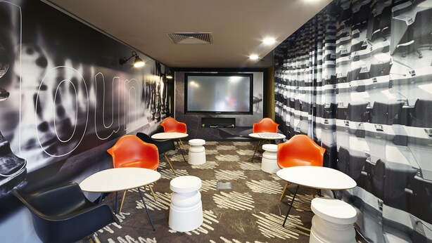 A modern cinema room with a large screen, comfortable seating, and a patterned carpet. - ibis Marne La Vallée Champs (Champs-sur-Marne)