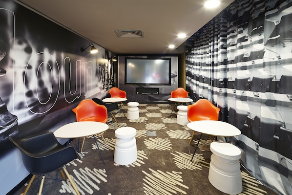 A modern cinema room with a large screen, comfortable seating, and a patterned carpet.