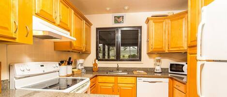 A kitchen with wooden cabinets, a white stove, a microwave, and a dishwasher.