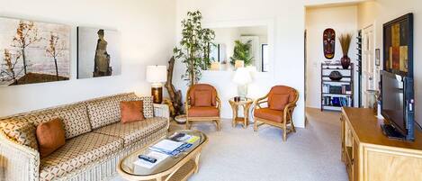 Un salon comprenant un canapé, deux fauteuils, une table basse et un meuble pour la télévision.