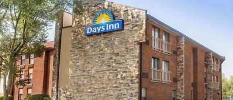 Un bâtiment de la chaîne Days Inn avec une façade en pierre, de nombreuses fenêtres et un ciel dégagé.