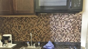 A kitchen with dark wooden cabinets, a stainless steel sink, a microwave, and a stove.