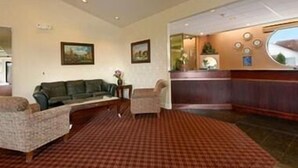 A hotel lobby with a checkered carpet, a reception desk, a sofa, and two armchairs.