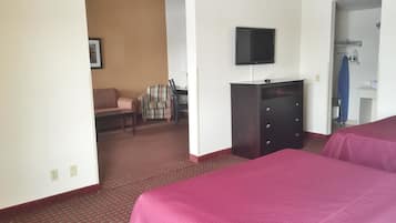 Una camera d'albergo con un letto, una scrivania, una sedia, una televisione e un armadio.