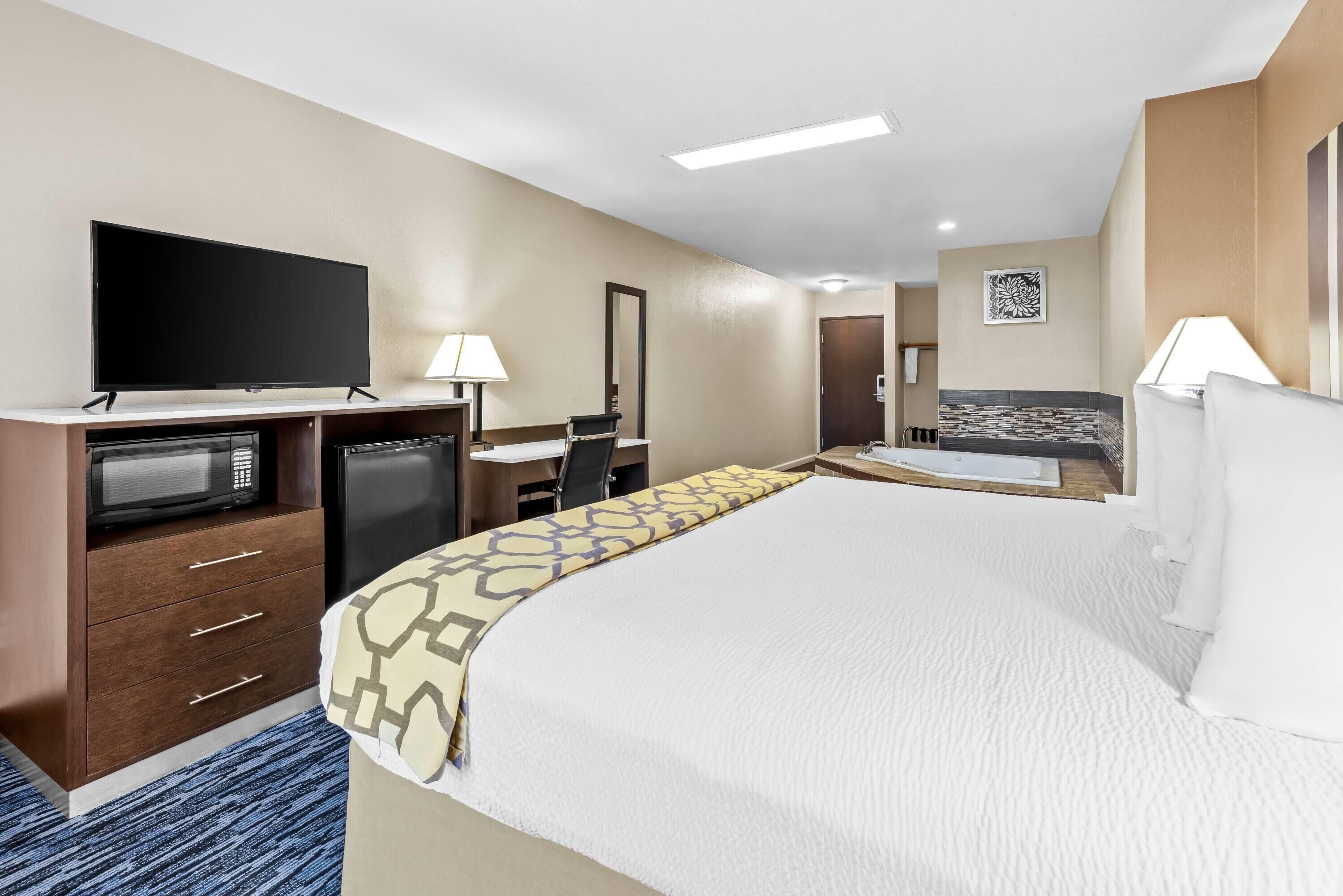 Ein Hotelzimmer mit einem Bett, einem Schreibtisch, einem Fernseher, einer Mikrowelle und einem Kühlschrank.