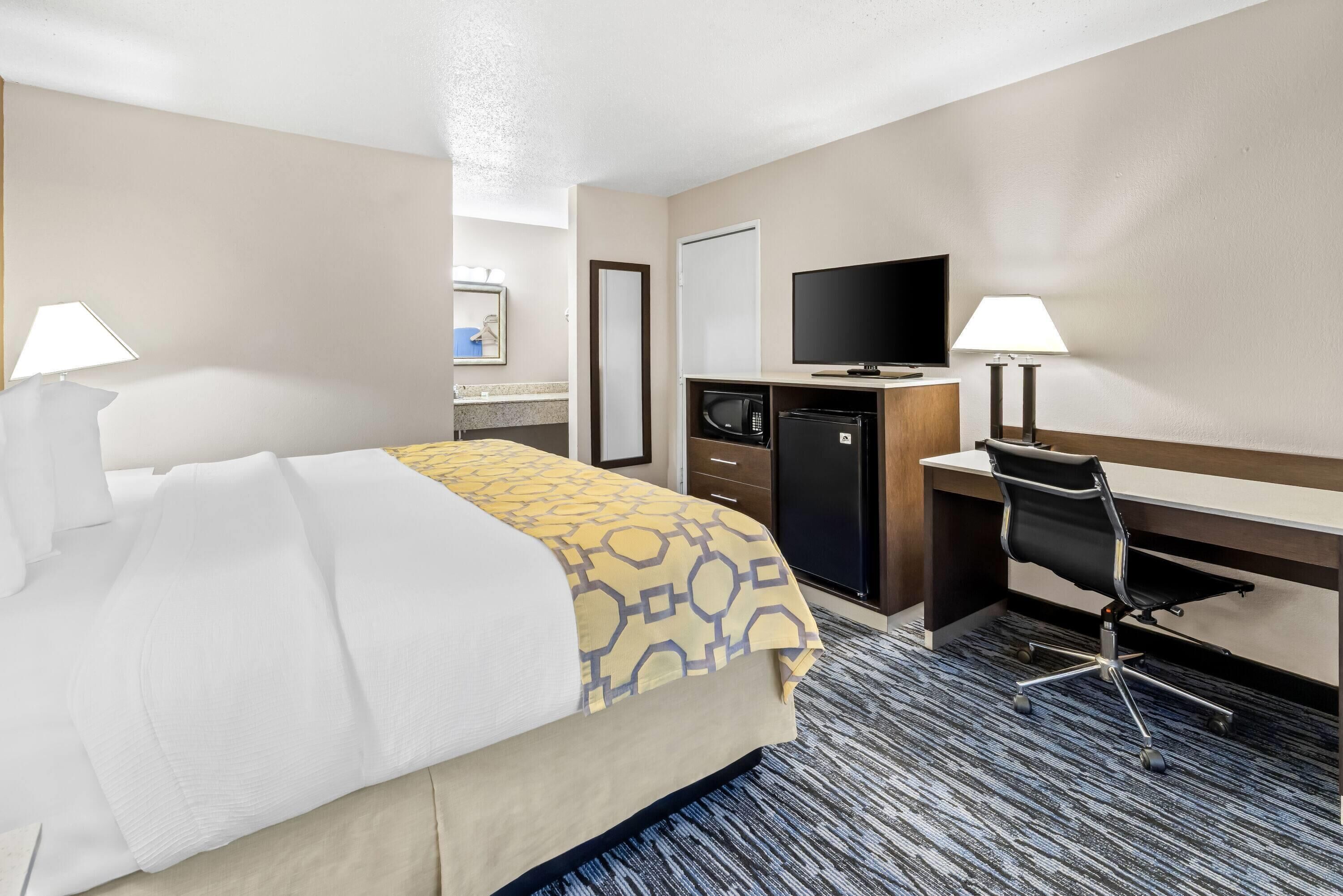 Une chambre d’hôtel équipée d’un lit, d’un bureau, d’une télévision, d’un four à micro-ondes et de deux lampes.