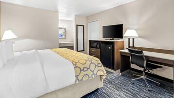 Une chambre d’hôtel équipée d’un lit, d’un bureau, d’une télévision, d’un four à micro-ondes et de deux lampes.