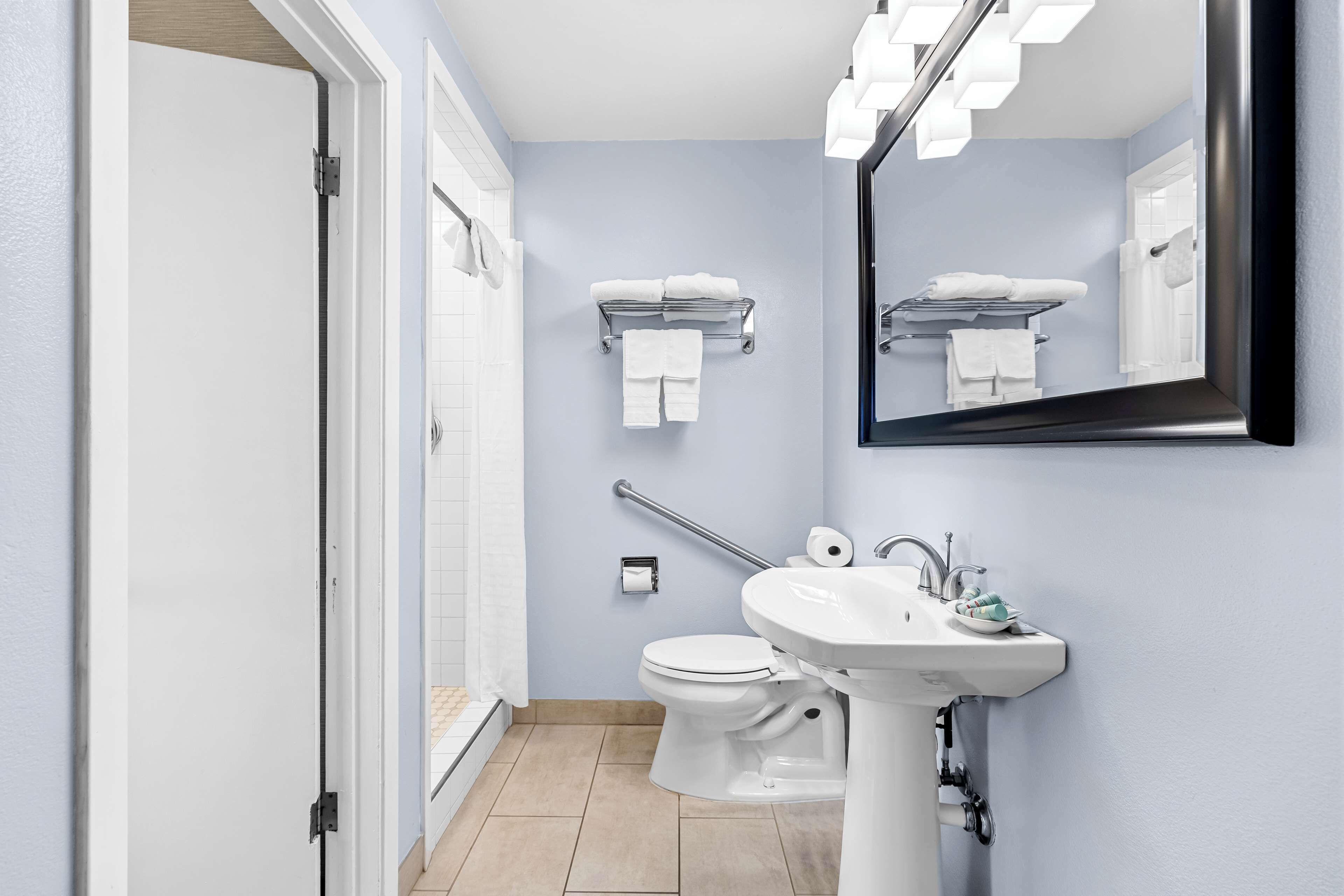 Un baño moderno con inodoro blanco, lavamanos y espejo.