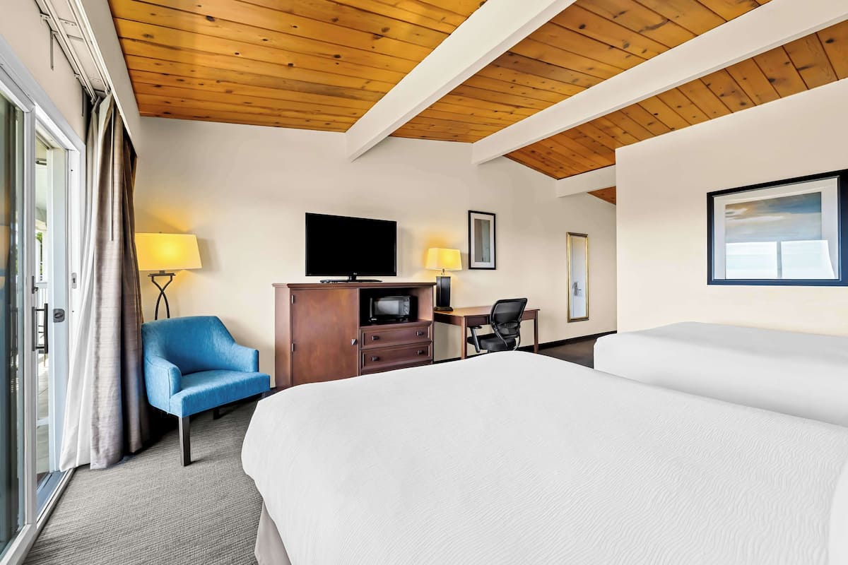 A hotel room with a large bed, a desk with a computer, a TV, and a blue chair.