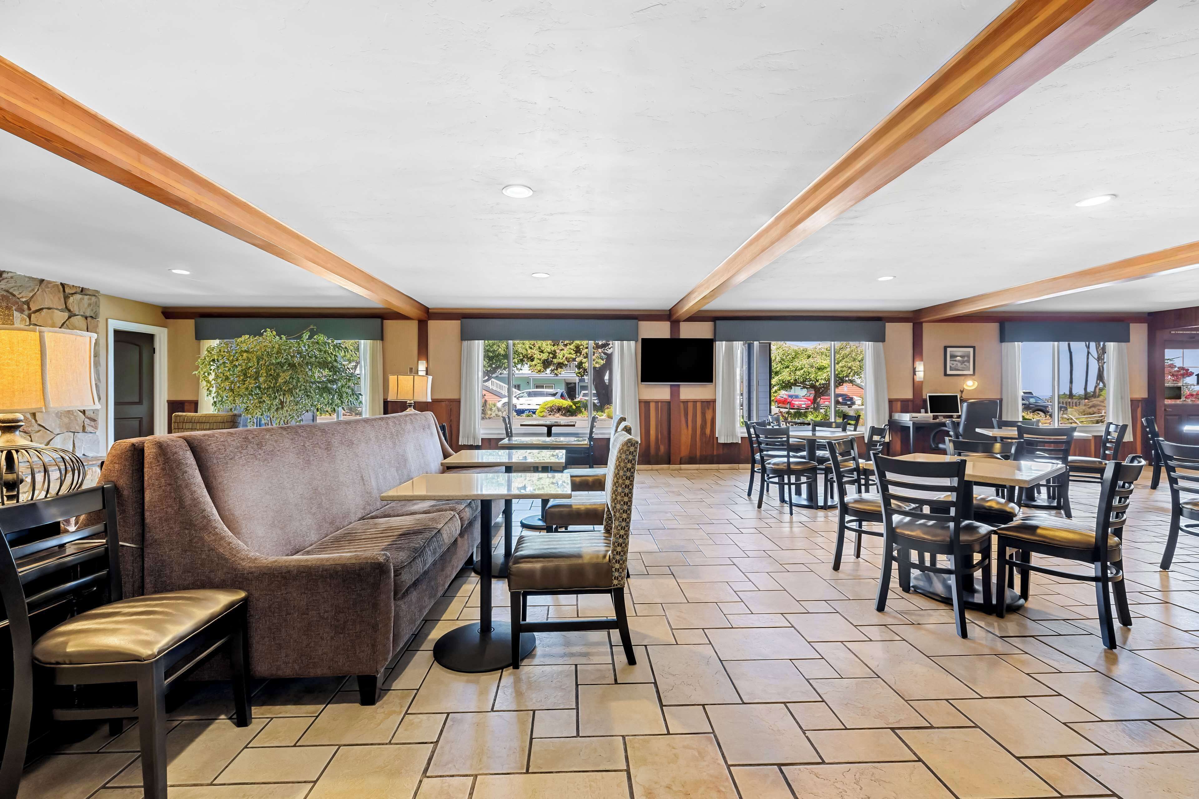 A spacious indoor area with a sofa, chairs, tables, and a television.