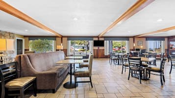 A spacious indoor area with a sofa, chairs, tables, and a television.