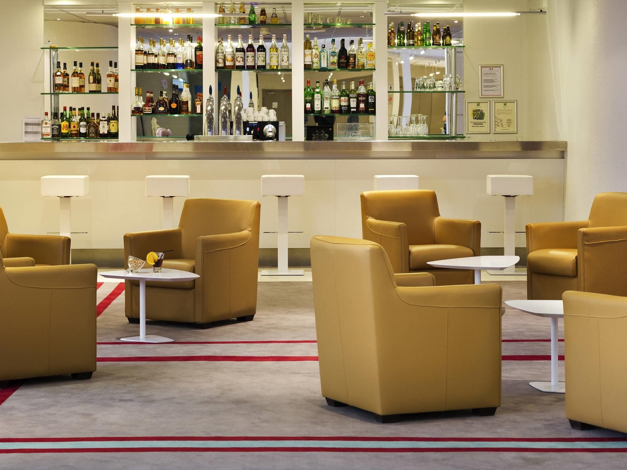 A bar area with multiple seating options and a variety of liquor bottles.