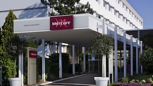 En modern byggnad med en vit fasad, en överbyggd entré och en skylt som visar att det är ett Mercure-hotell.