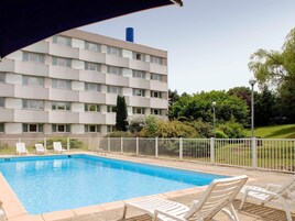 Una piscina al aire libre de temporada, sillones reclinables de piscina