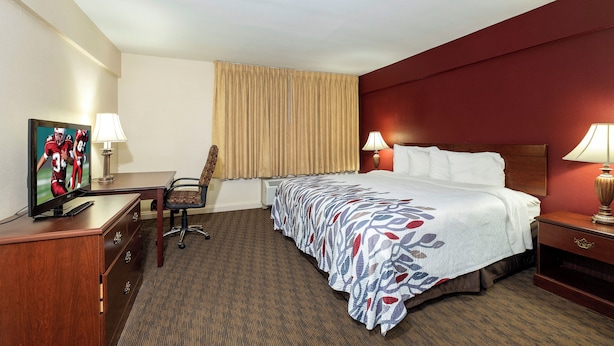 A hotel room with a bed, desk, chair, and a television on a dresser. - Red Roof Inn & Suites Hazleton (Hazleton)