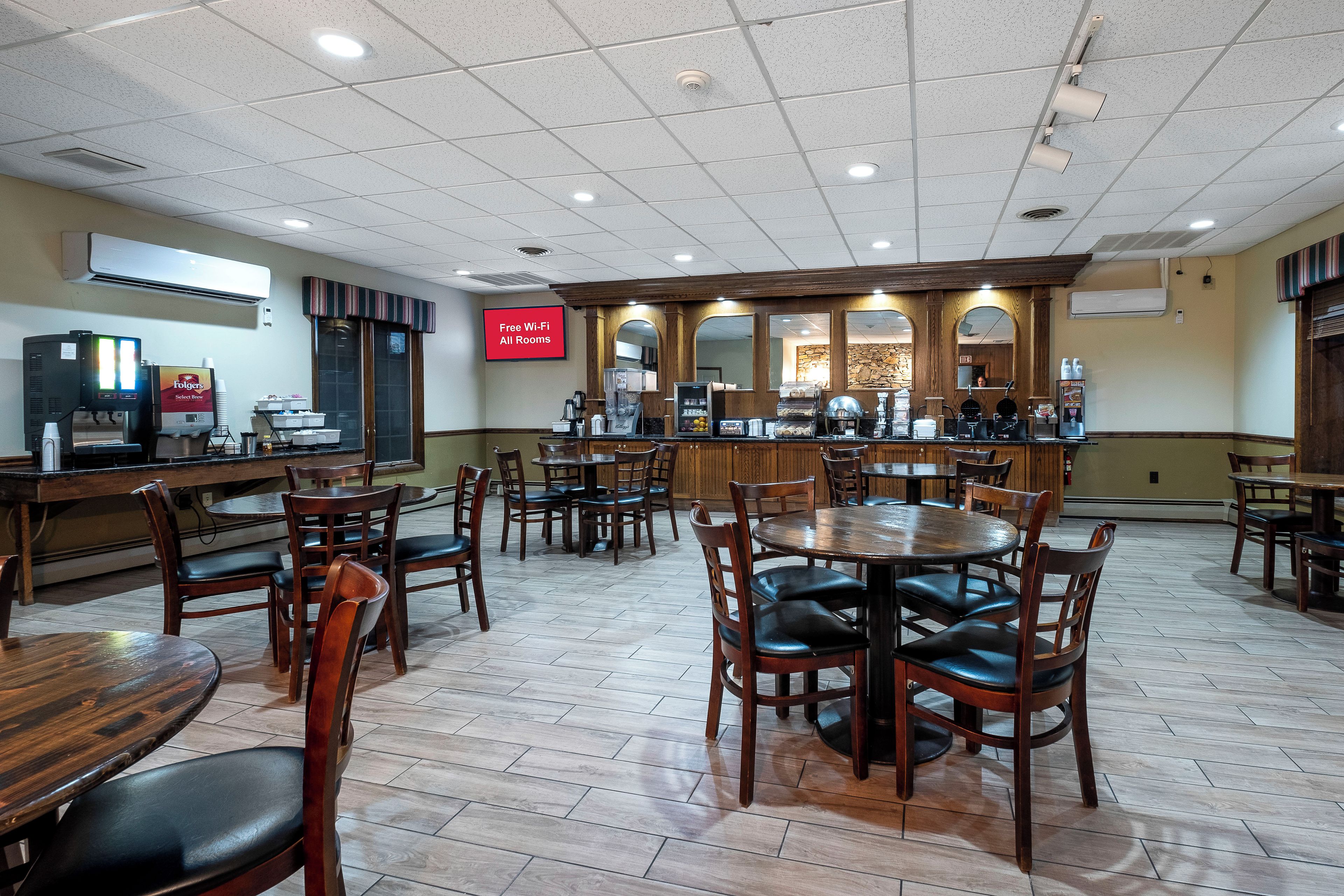 A restaurant with multiple tables and chairs, a coffee machine, and a menu board.