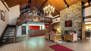 A spacious lobby with a wooden staircase, a stone fireplace, and a Red Roof Inn sign. - Red Roof Inn & Suites Hazleton (Hazleton)
