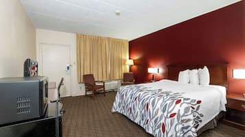 A hotel room with a bed, a desk, a chair, a television, and a window with curtains.