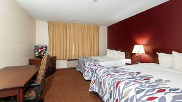 A hotel room with a bed, a desk, a chair, a television, and a lamp.