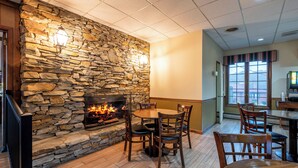 A cozy restaurant interior with a stone fireplace, wooden furniture, and a view through the window. - Red Roof Inn & Suites Hazleton (Hazleton)
