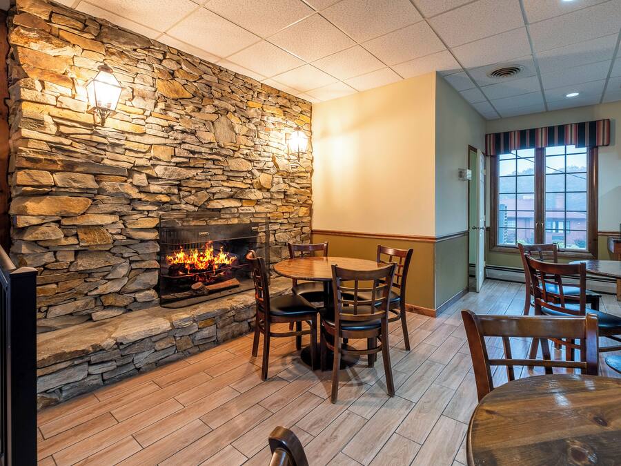 Ein gemütliches Restaurantambiente mit Kamin aus Stein, Holzmöbeln und Blick durch das Fenster.