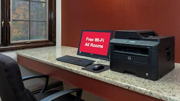 A desk with a Dell computer, a printer, and a sign indicating free Wi-Fi in all rooms.