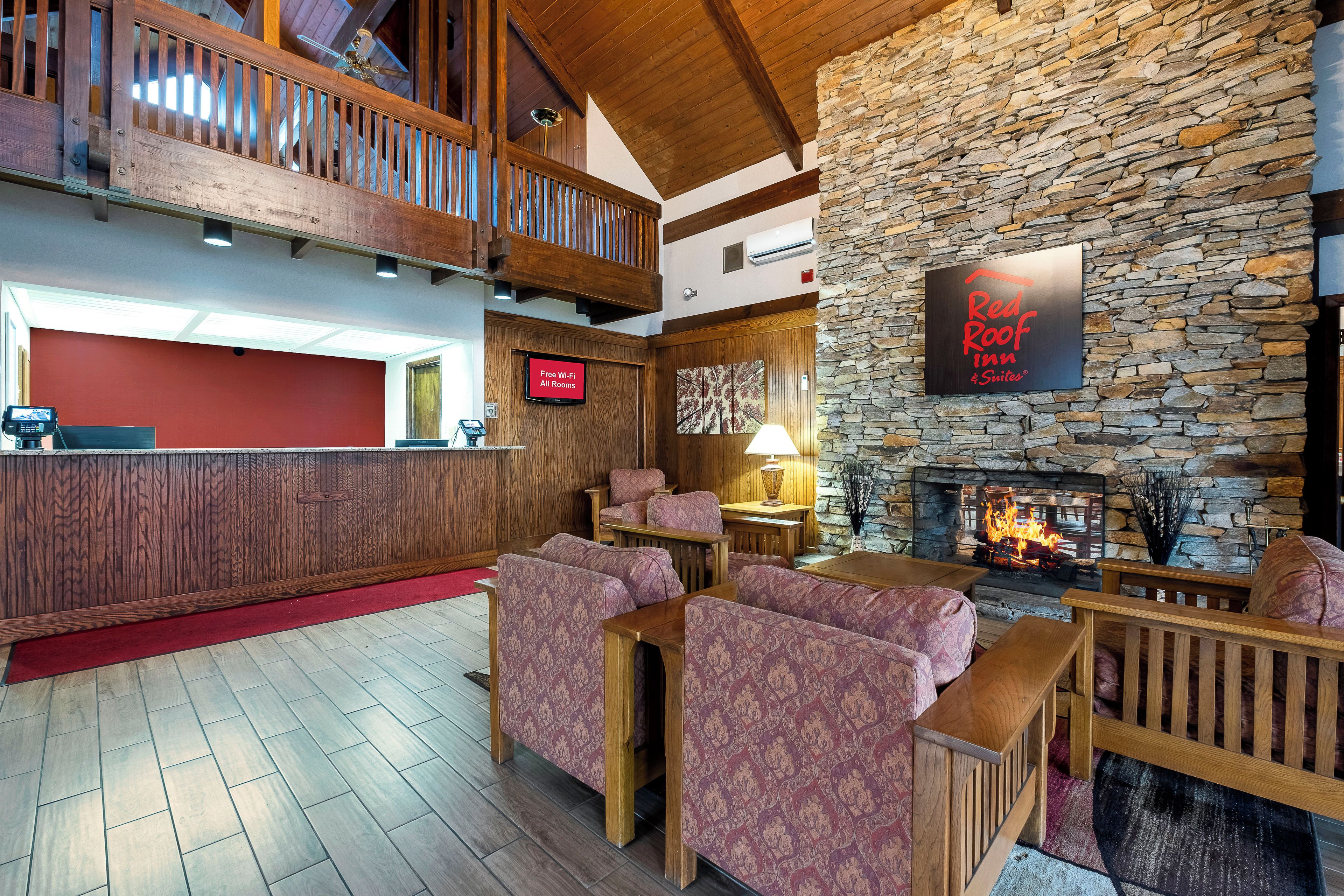 A hotel lobby with a stone wall, a fireplace, and a sign for Red Roof Inn & Suites.