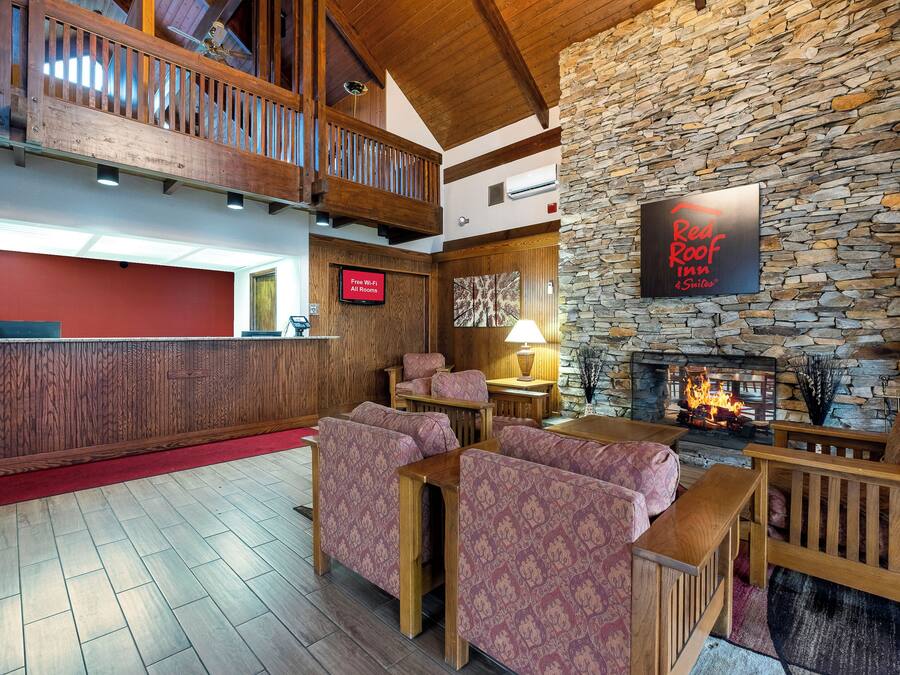 A hotel lobby with a stone wall, a fireplace, and a sign for Red Roof Inn & Suites.