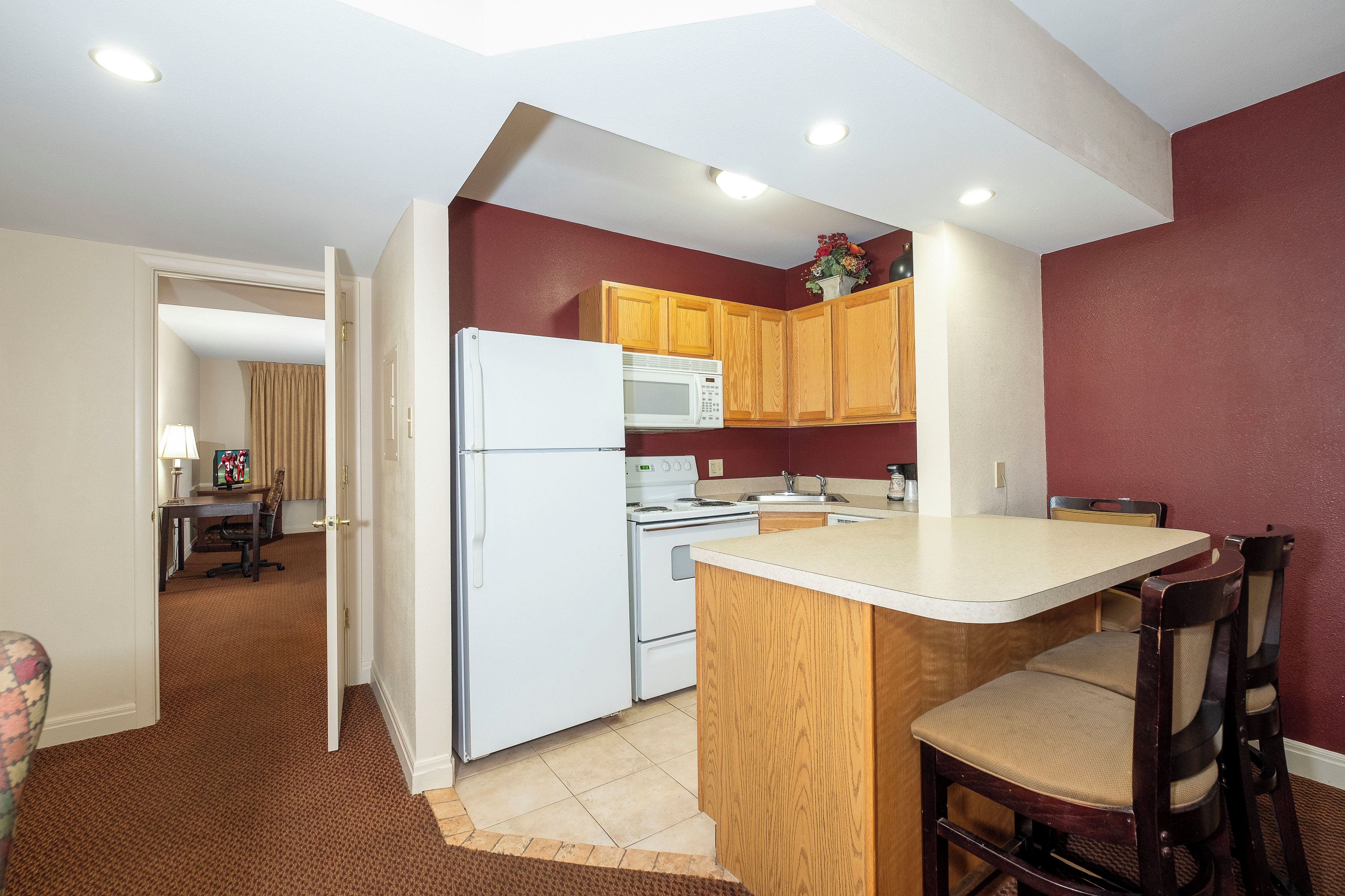 A compact kitchen with a refrigerator, microwave, and wooden cabinets.