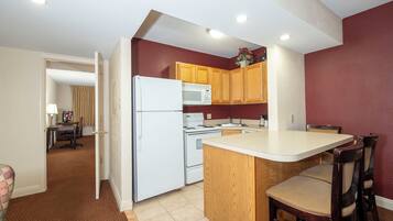 A compact kitchen with a refrigerator, microwave, and wooden cabinets.