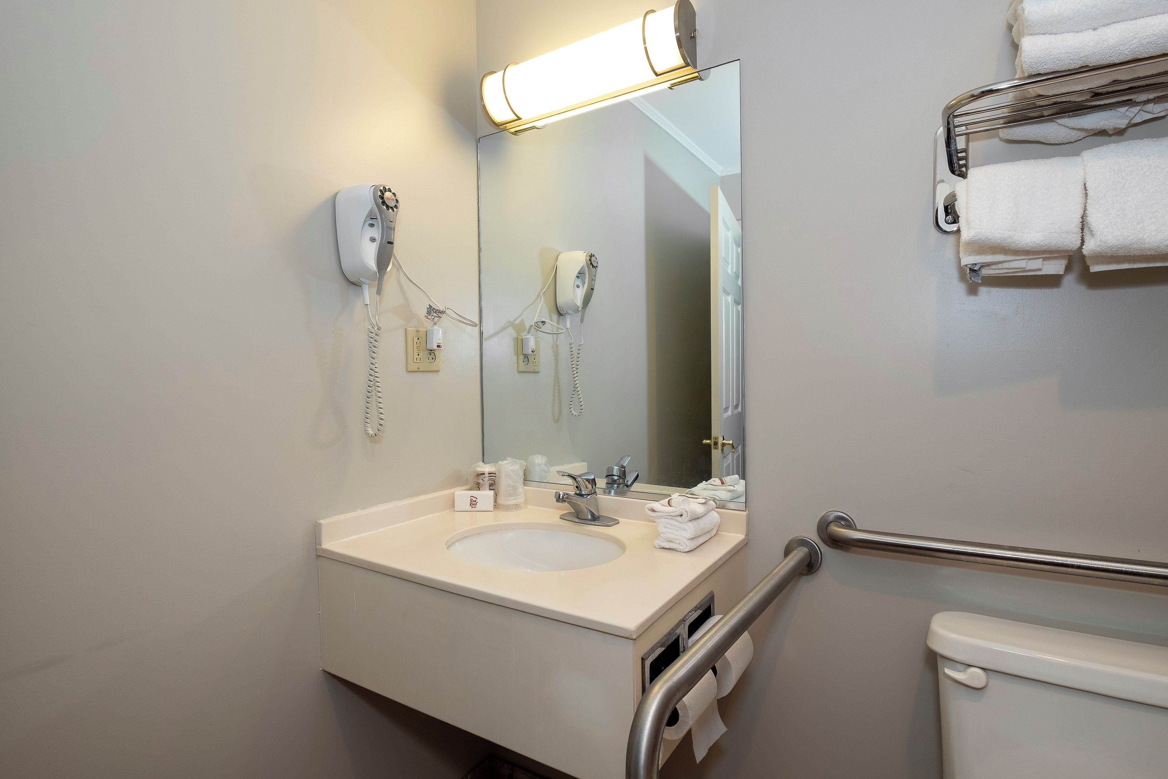 A bathroom with a sink, mirror, towel rack, and a toilet.