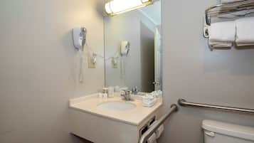 A bathroom with a sink, mirror, towel rack, and a toilet.