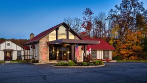 A building with a stone facade, a red roof, and two American flags. - Red Roof Inn & Suites Hazleton (Hazleton)