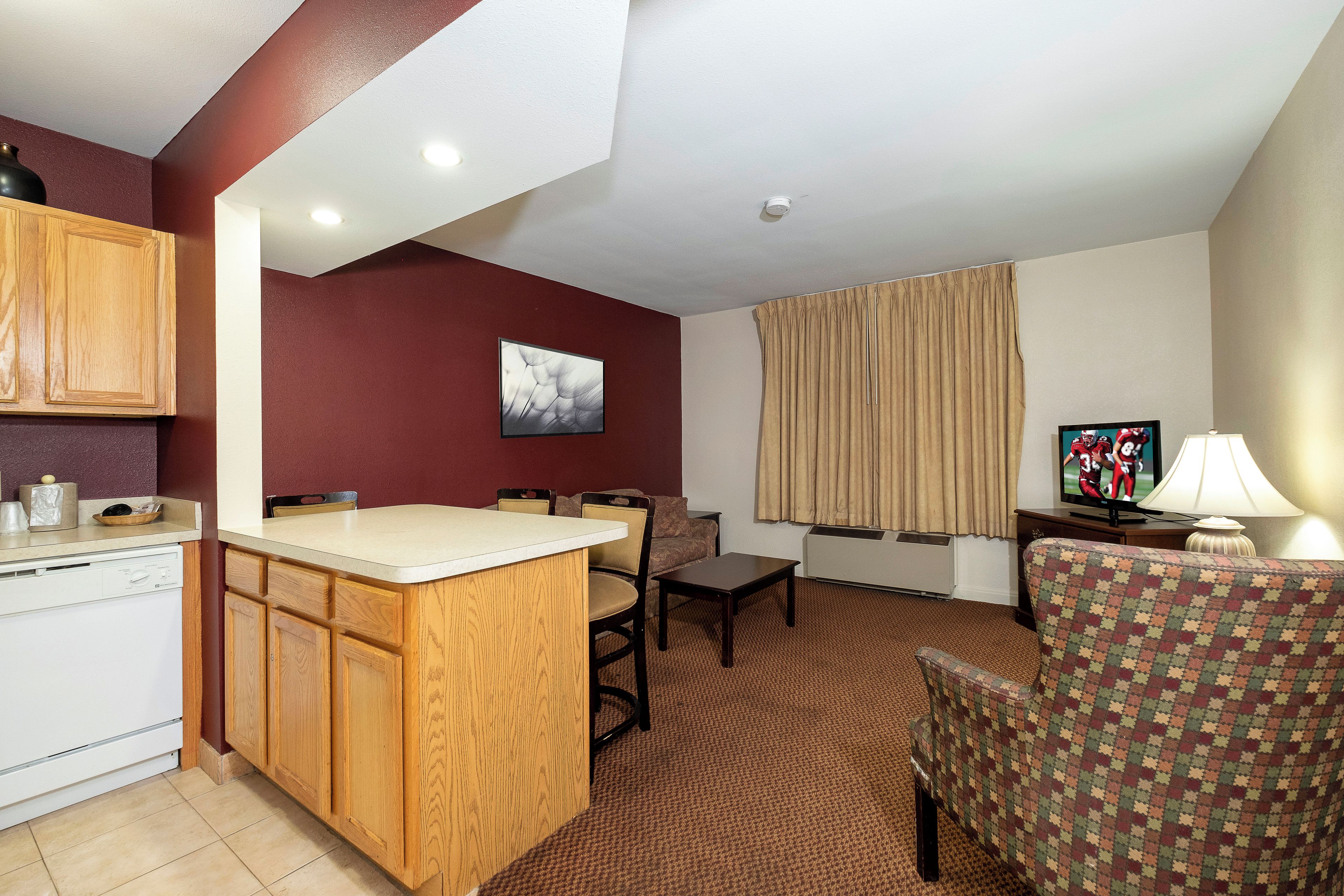 Un espacio habitable compacto con kitchenette, zona de comedor y sala de estar con televisión.