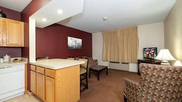 Un espacio habitable compacto con kitchenette, zona de comedor y sala de estar con televisión.