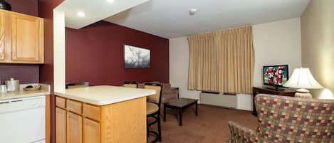 A compact living space with a kitchenette, a dining area, and a seating area with a television.