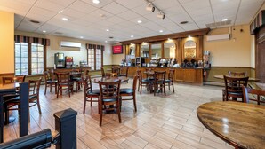 A spacious restaurant with multiple tables and chairs, a bar area, and a digital menu display. - Red Roof Inn & Suites Hazleton (Hazleton)