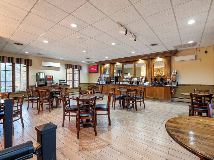 Un restaurante espacioso con varias mesas y sillas, una zona de bar y una pantalla digital con el menú.
