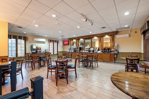 A spacious restaurant with multiple tables and chairs, a bar area, and a digital menu display. - Red Roof Inn & Suites Hazleton (Hazleton)