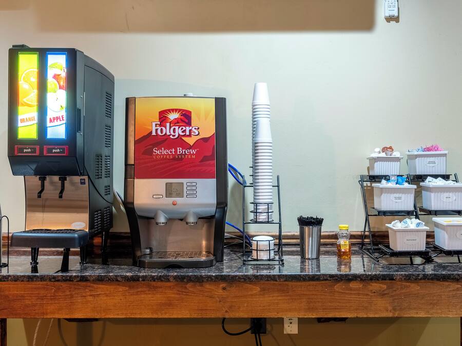 A coffee station with a Folgers Select Brew coffee system, disposable cups, and various coffee pods.