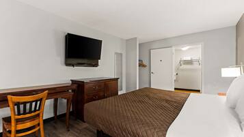 A hotel room with a bed, a desk, a chair, a television, and a wardrobe.