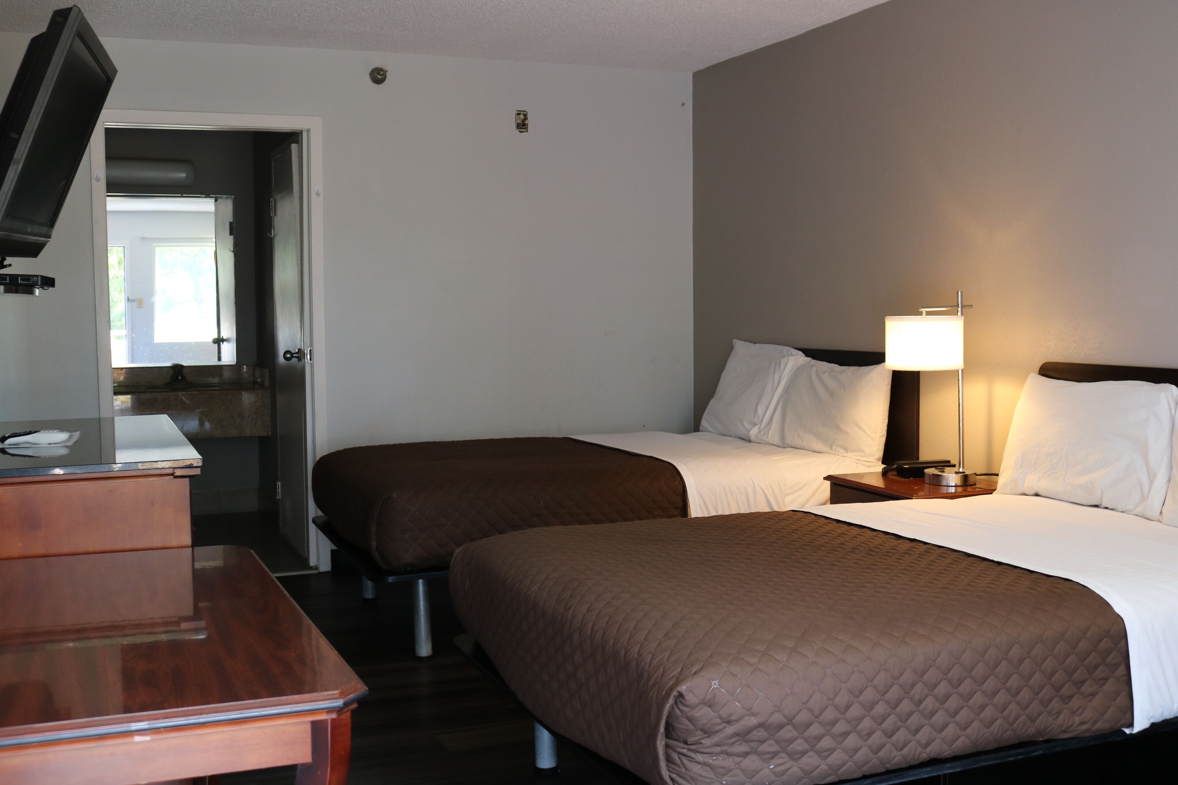 A hotel room with two beds, a desk, and a TV.