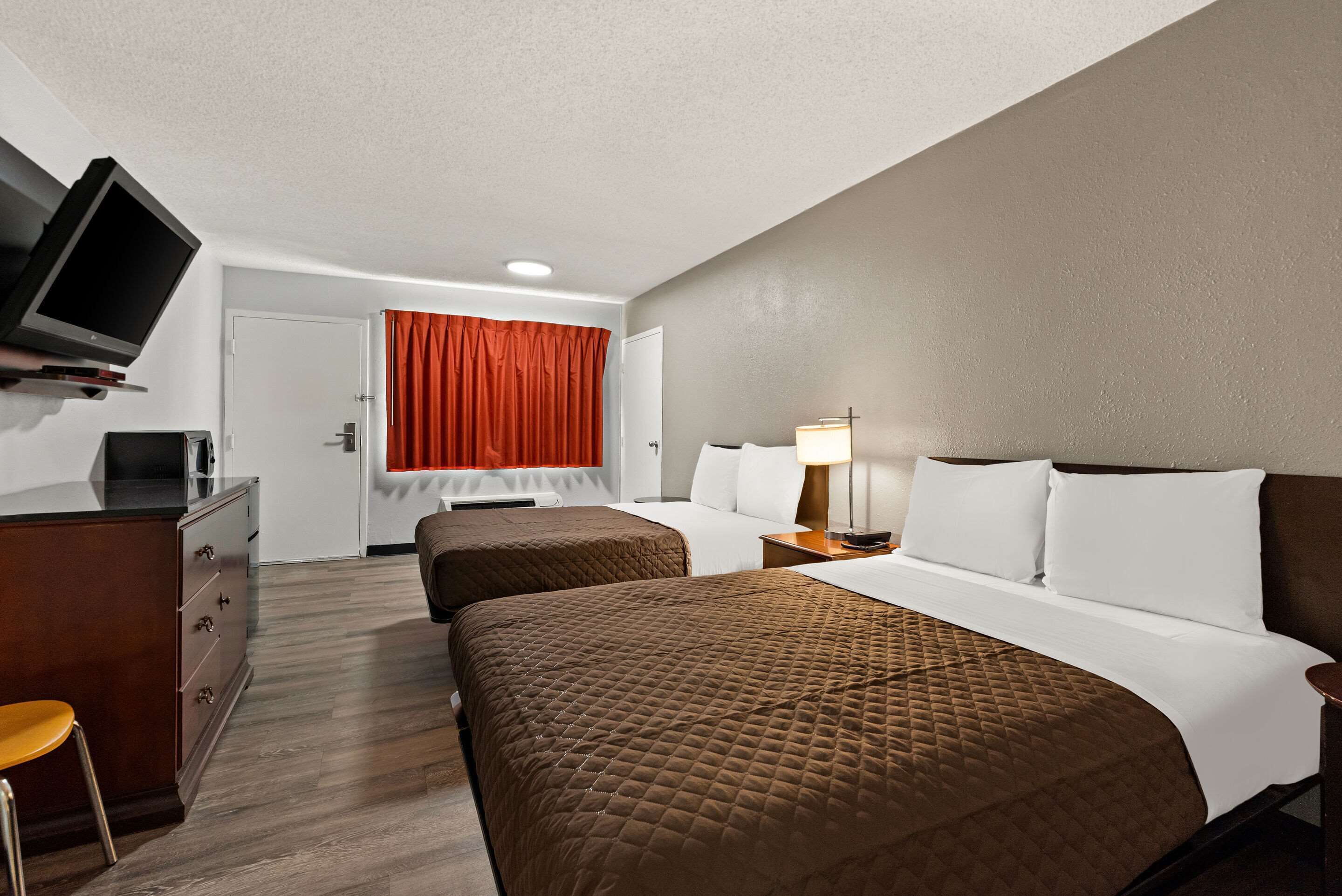 A hotel room with two beds, a TV, a desk, and a chair.