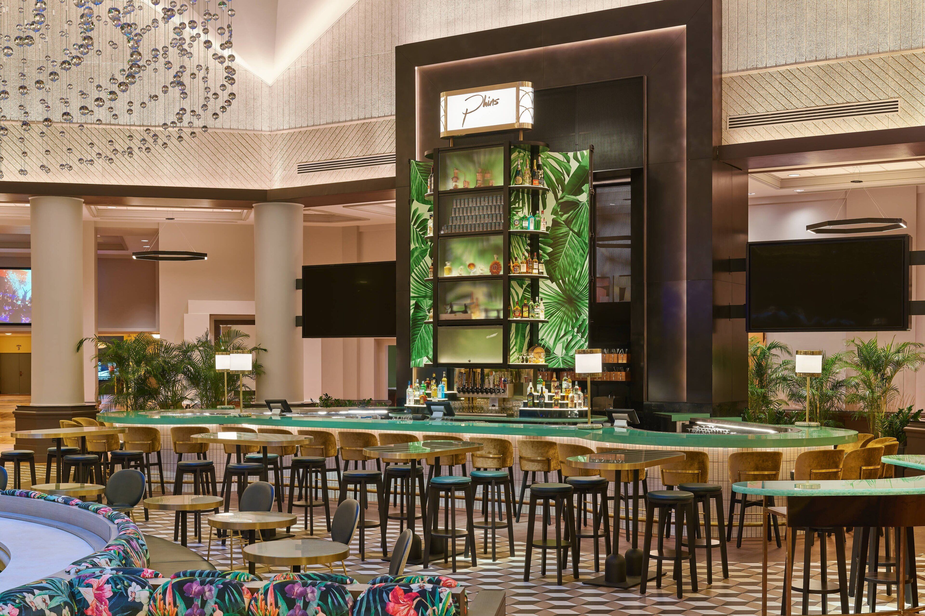 A spacious lobby with a bar area, multiple seating arrangements, and a large screen.