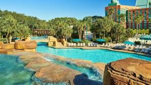 A hotel pool area with clear water, palm trees, and lounge chairs. - Walt Disney World Swan (Lake Buena Vista)